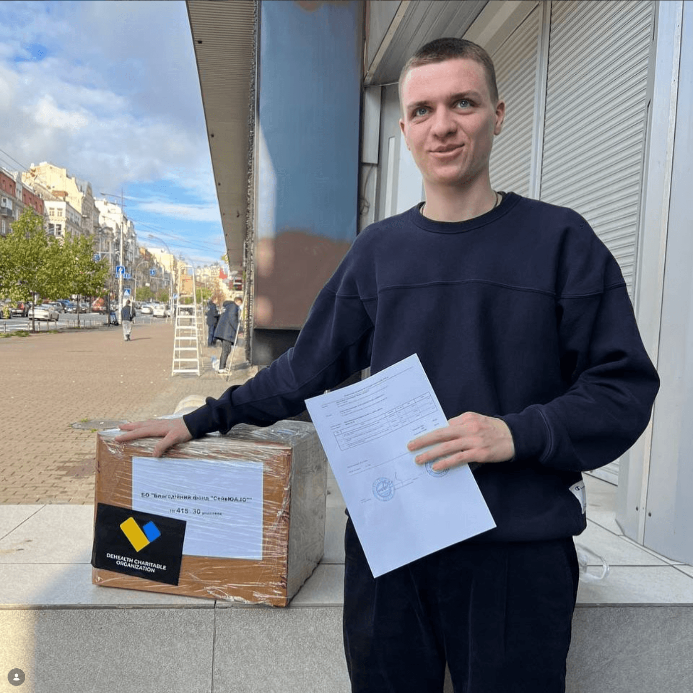 Представник фонду «SaveUA» з коробкою медикаментів від DeHealth та супровідними документами на вулиці у Києві